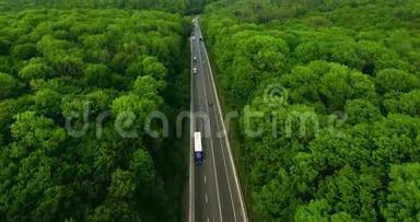 空中景色随着汽车的移动飞越公路，那穿过车道的绿色森林。 汽车沿林路行驶.. 汽车轮胎